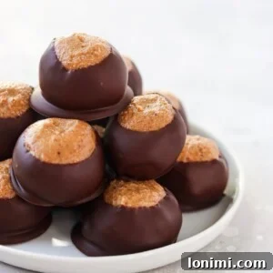 Perfectly dipped Paleo Buckeye Balls, arranged on parchment paper, ready to be chilled.