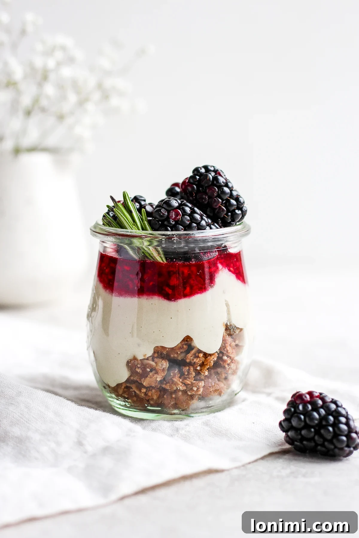 Individual Vegan Paleo Blackberry Cheesecake Jars, garnished with fresh blackberries and mint, showcasing layers of creamy dessert.