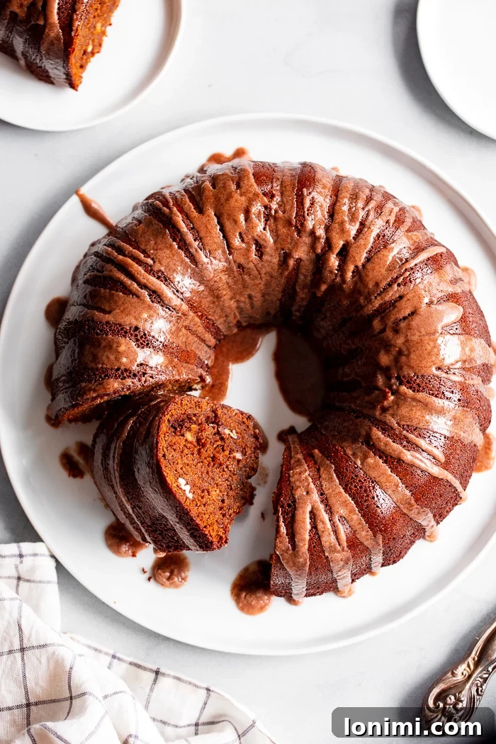 A beautifully decorated Paleo Gingerbread Bundt Cake, dusted with powdered sugar and surrounded by festive greenery.