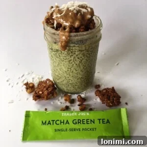 A top-down view of a glass jar filled with green matcha chia pudding, adorned with fresh toppings.