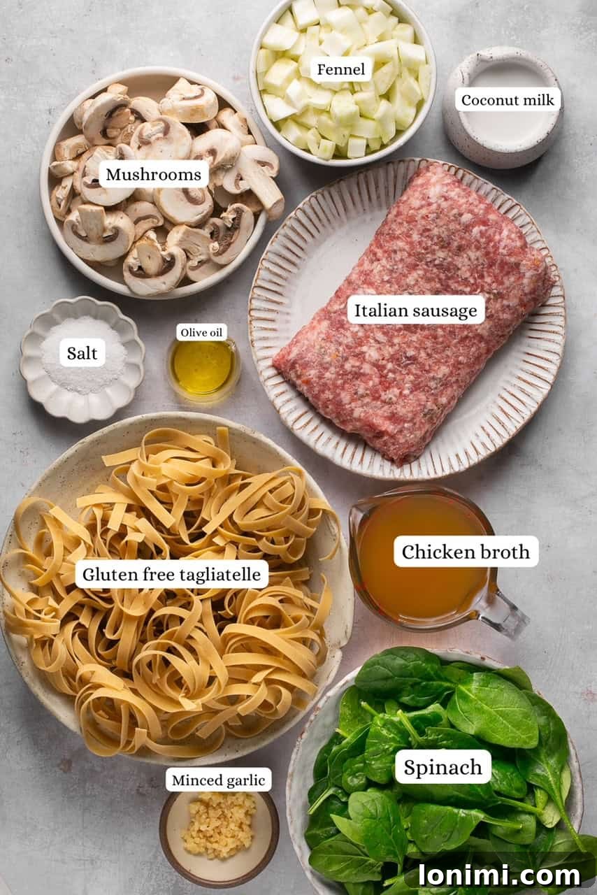Quick and Flavorful Gluten-Free Sausage and Fennel Pasta 3 A collection of fresh ingredients laid out on a wooden board, including Italian sausage, a whole fennel bulb, mushrooms, spinach, garlic cloves, chicken broth, and a box of gluten-free tagliatelle pasta, ready for cooking.