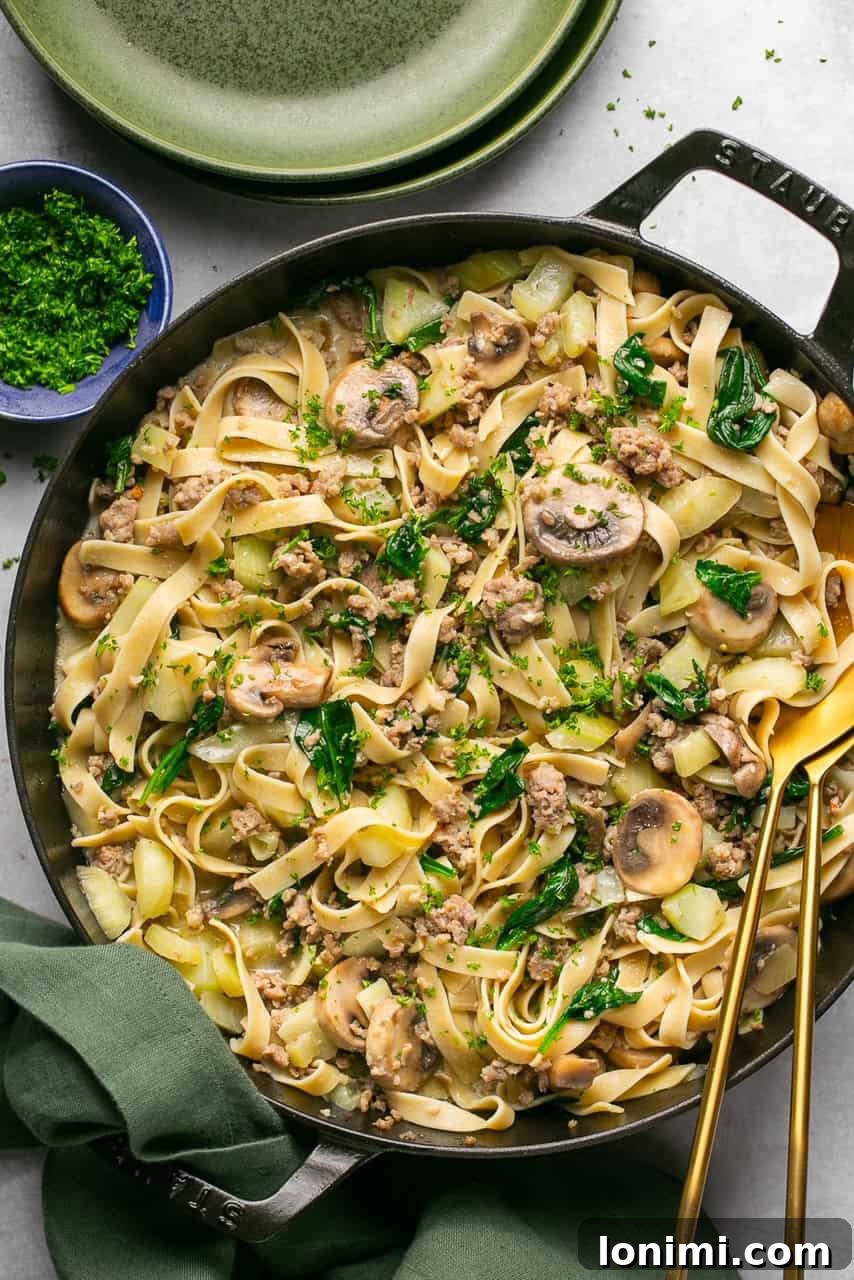 Quick and Flavorful Gluten-Free Sausage and Fennel Pasta 5 A vibrant close-up of the finished sausage and fennel pasta in a large cast iron skillet, with a green linen napkin artfully placed beside it, suggesting a rustic, home-cooked meal.