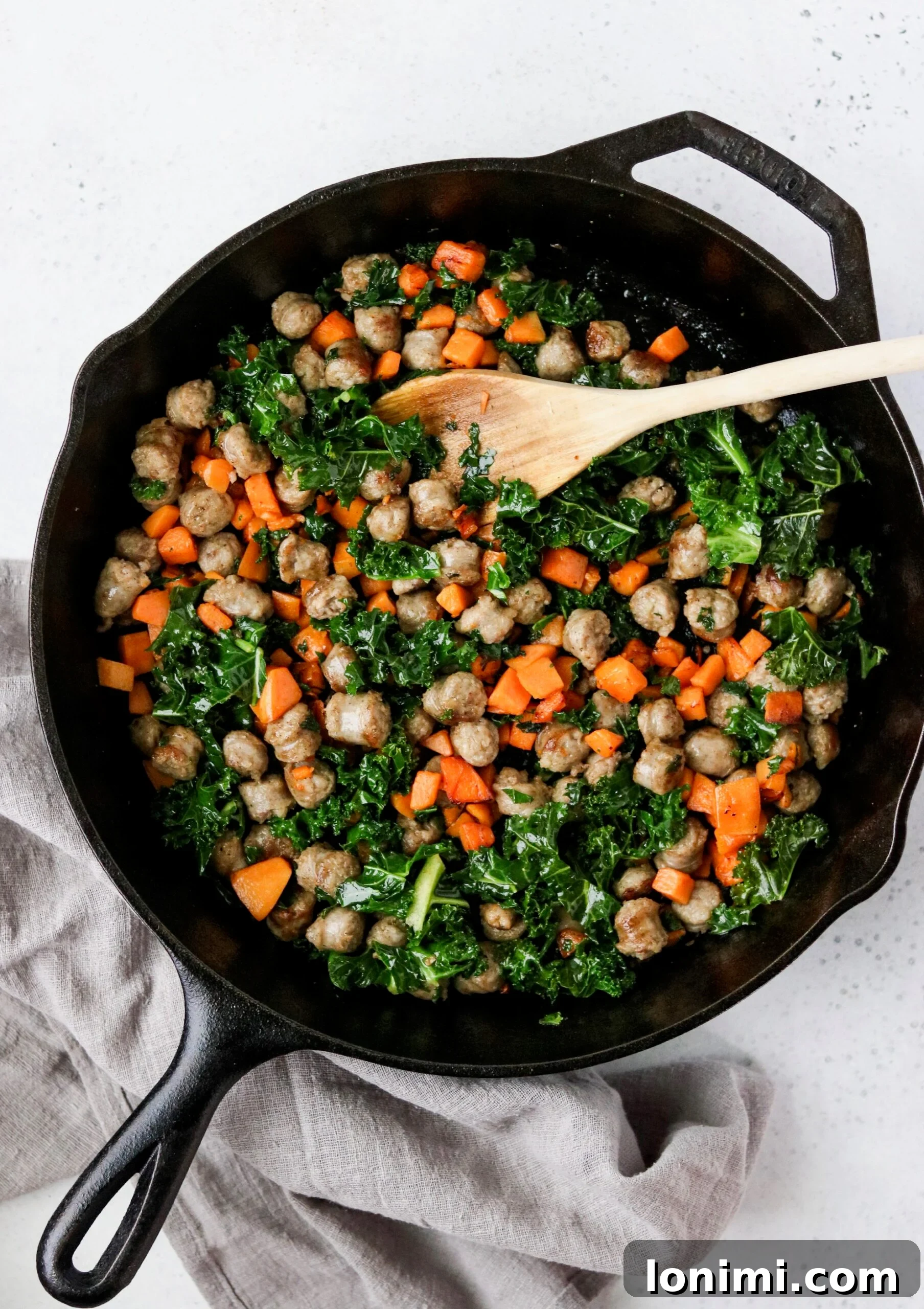 Close-up of cooked sausage, sweet potato, and kale filling in a cast iron skillet