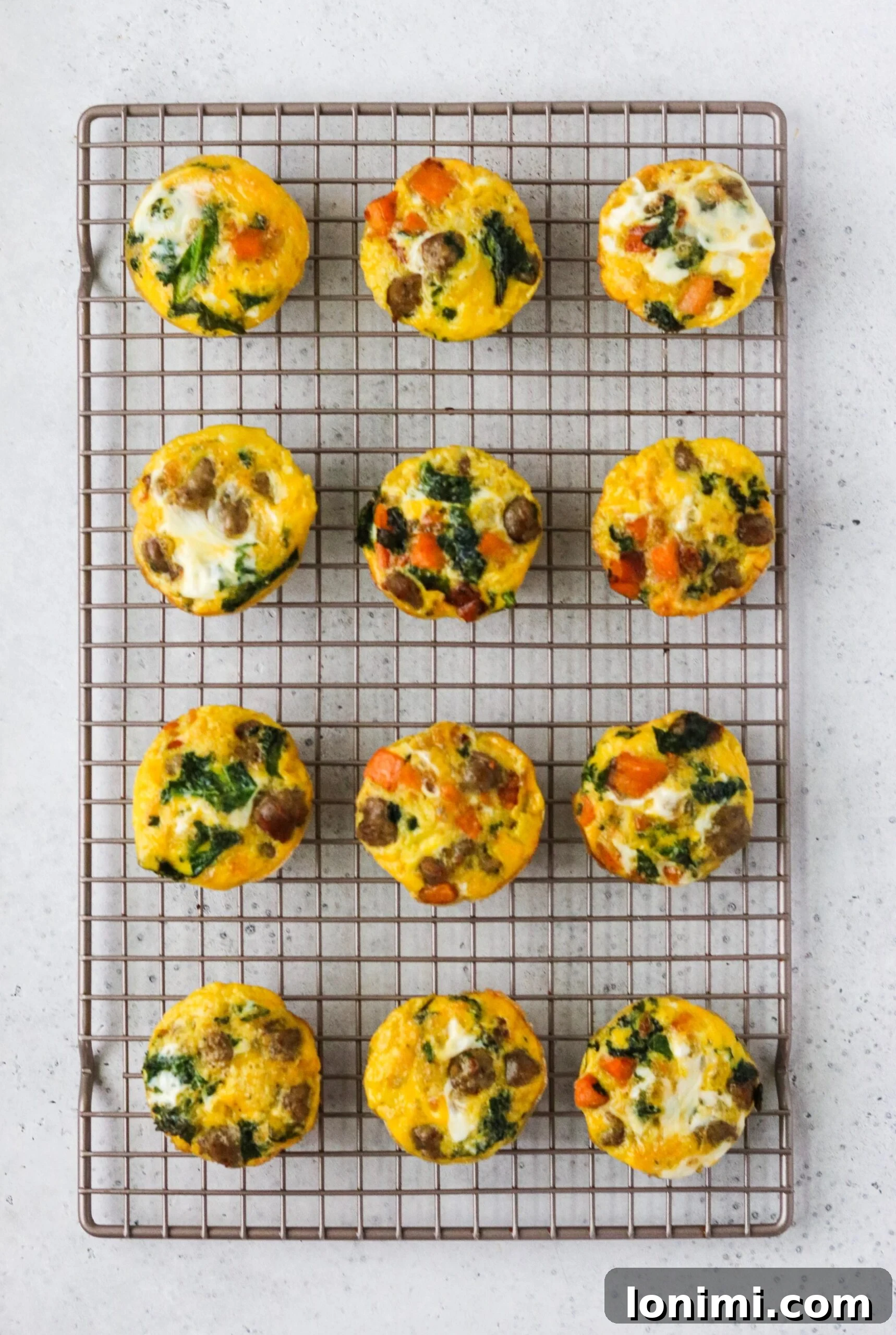 Freshly baked sausage, sweet potato, and kale egg cups on a cooling rack