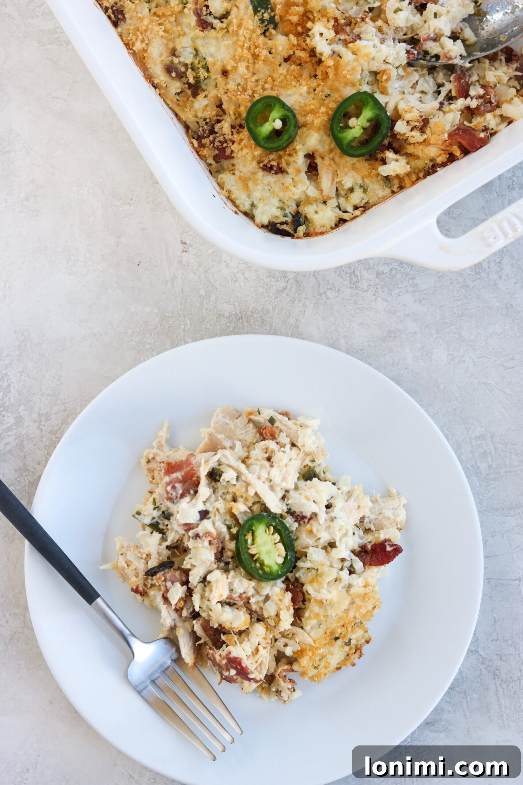 A small casserole dish, 8x11 inches, filled with the prepared Bacon Jalapeno Popper Chicken Casserole mixture before baking.