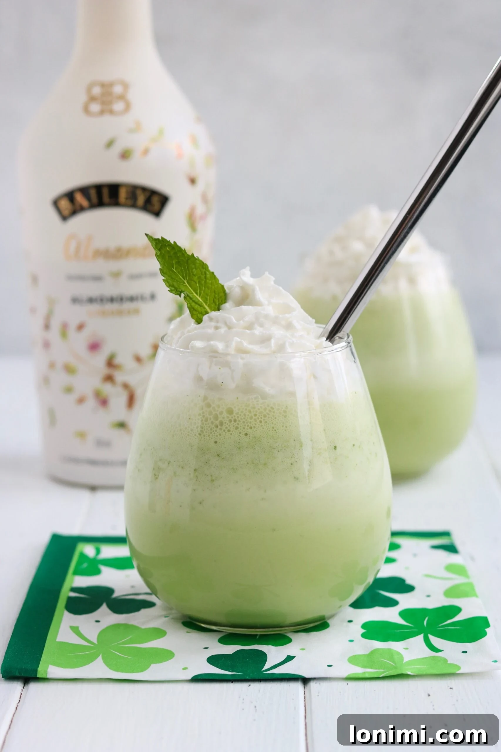 Spiked Shamrock Shake in a glass with whipped cream and a cherry, festive green drink.