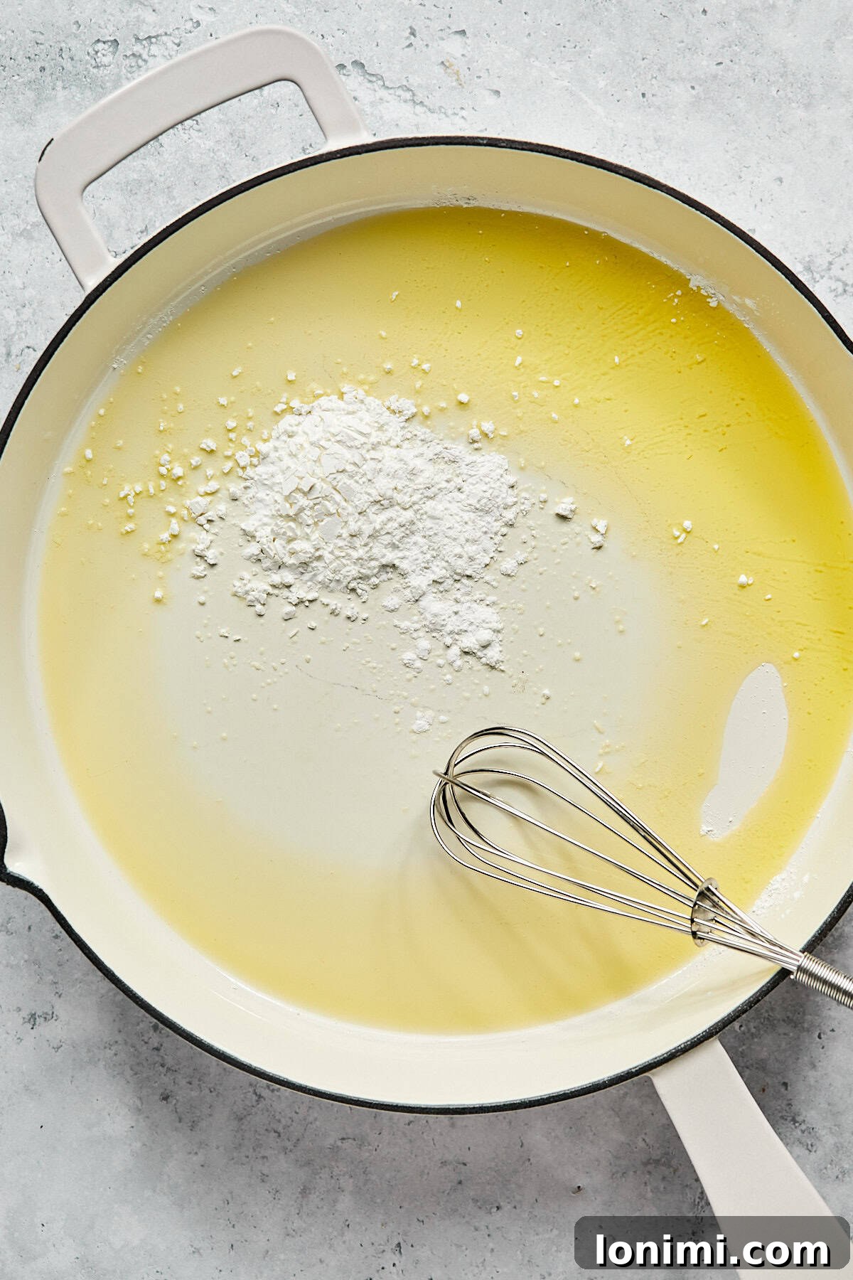 Ghee and tapioca flour being whisked together in a hot frying pan to form a roux for the gravy.