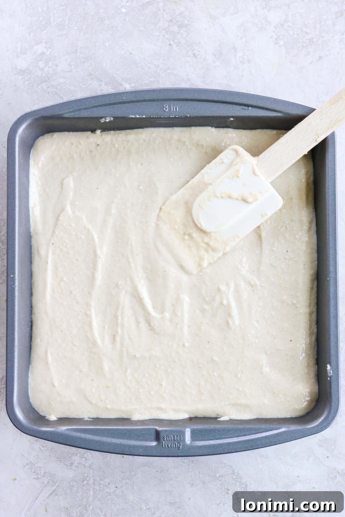 Cashew key lime pie bar filling being smoothly spread out on the prepared crust with a spatula.