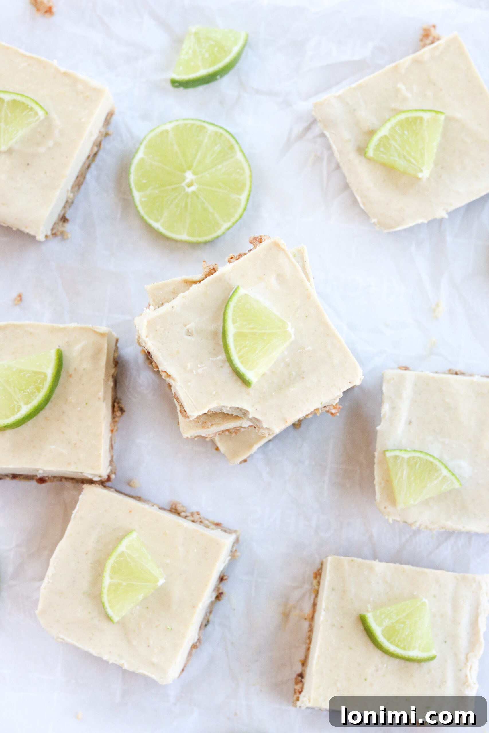 Several key lime pie bars artfully arranged on a piece of parchment paper.