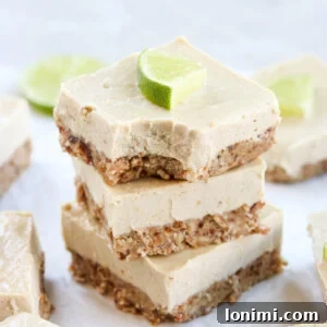 Vegan key lime cheesecake bars stacked on top of each other with a lime slice on top