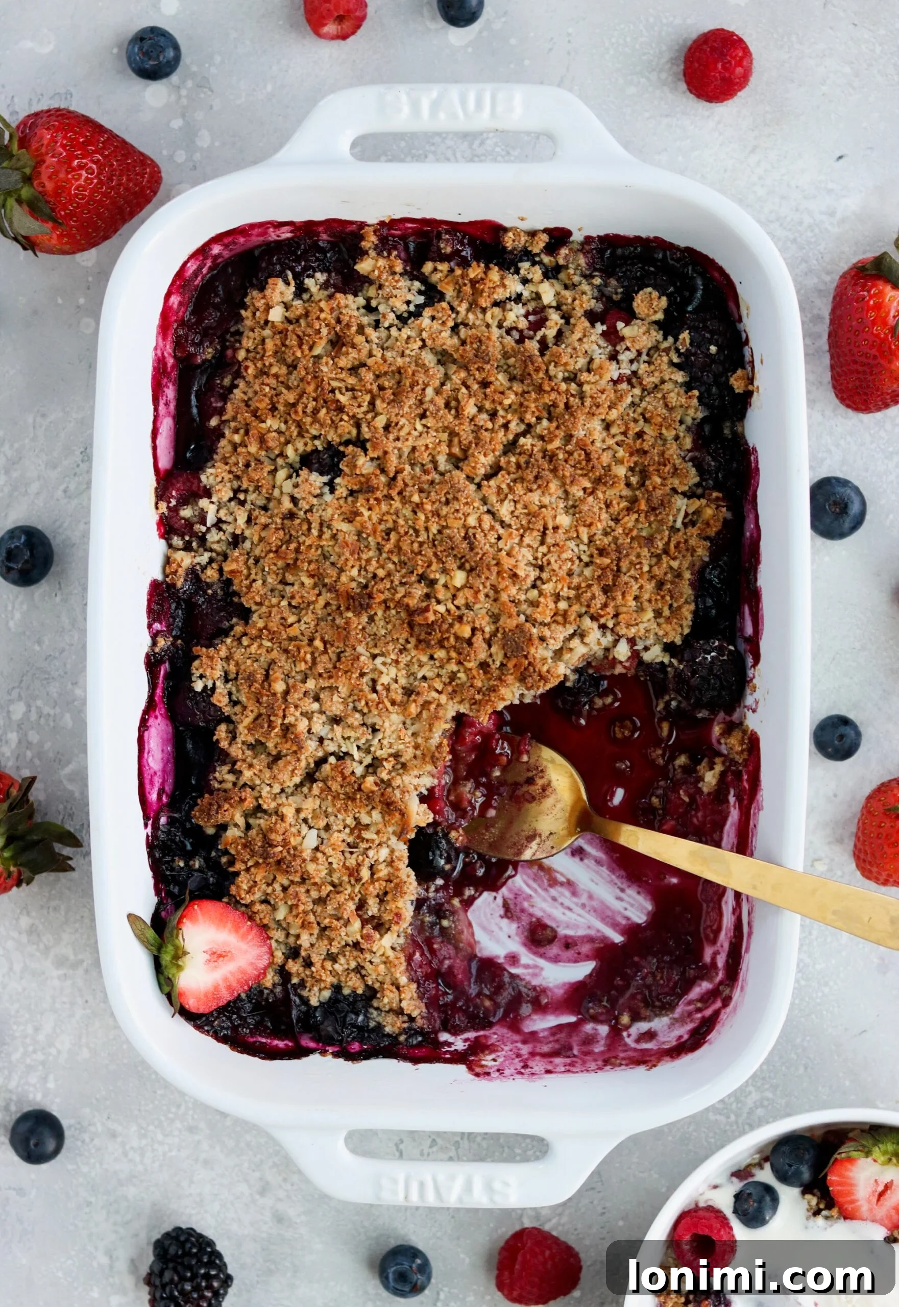 Delicious Paleo Vegan Berry Crisp dessert with mixed berries and crumble topping, served in a white baking dish.