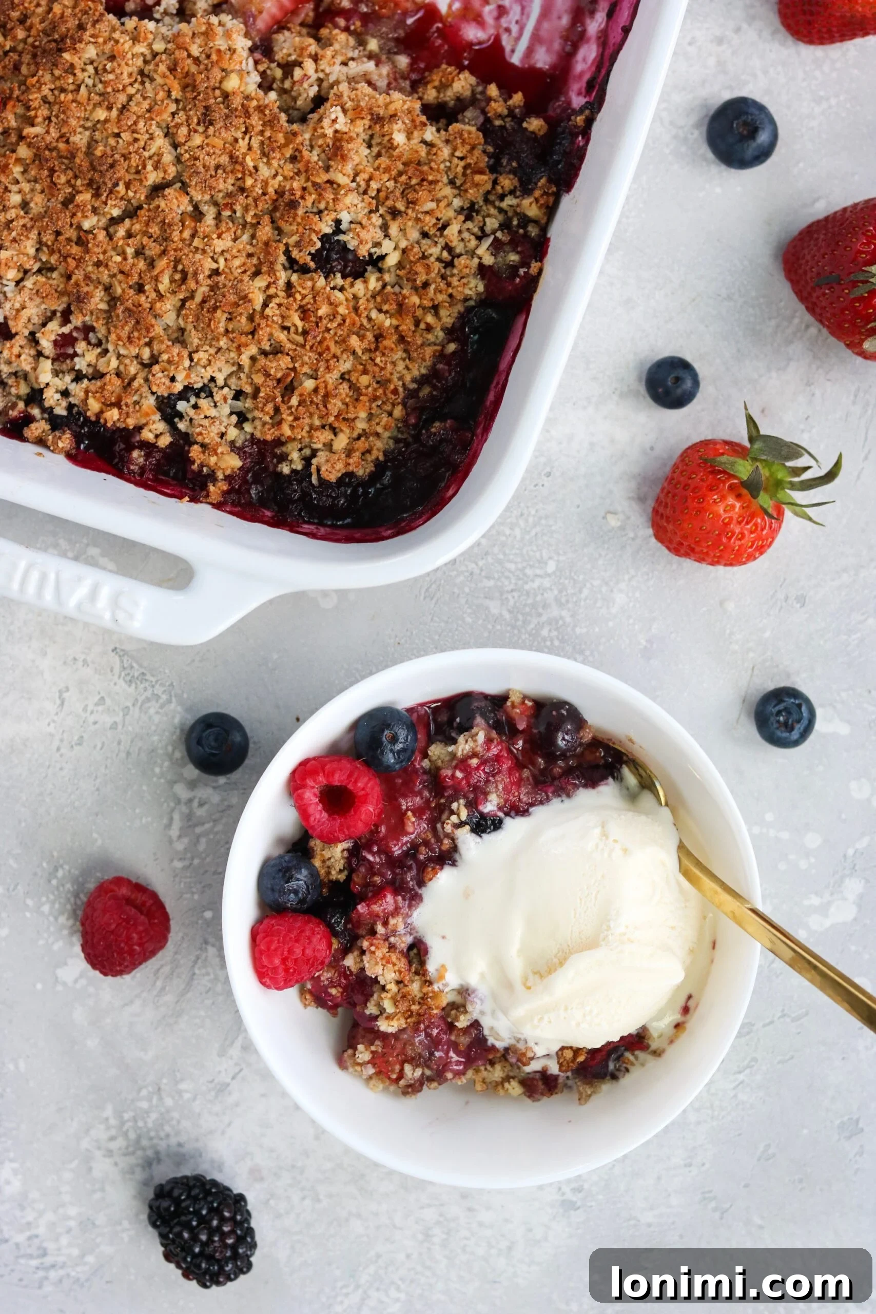 Single serving of Paleo Vegan Berry Crisp topped with vanilla coconut ice cream in a small bowl.