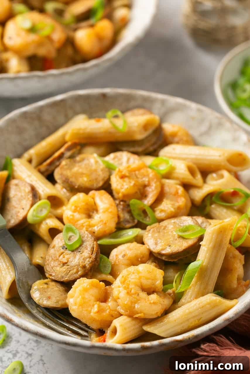 A close-up side view of creamy Cajun shrimp and sausage pasta, highlighting its rich texture and ingredients