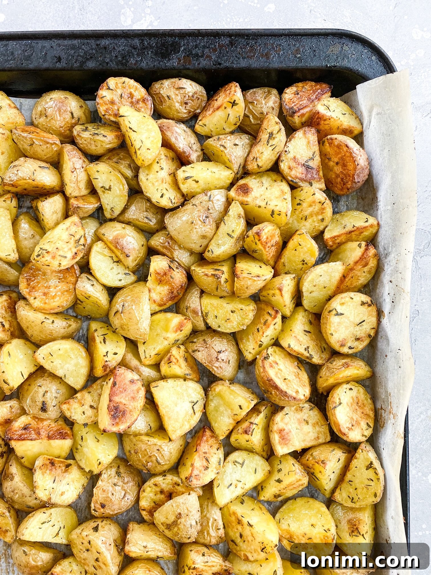 Close-up of golden brown herb roasted potatoes on a baking sheet