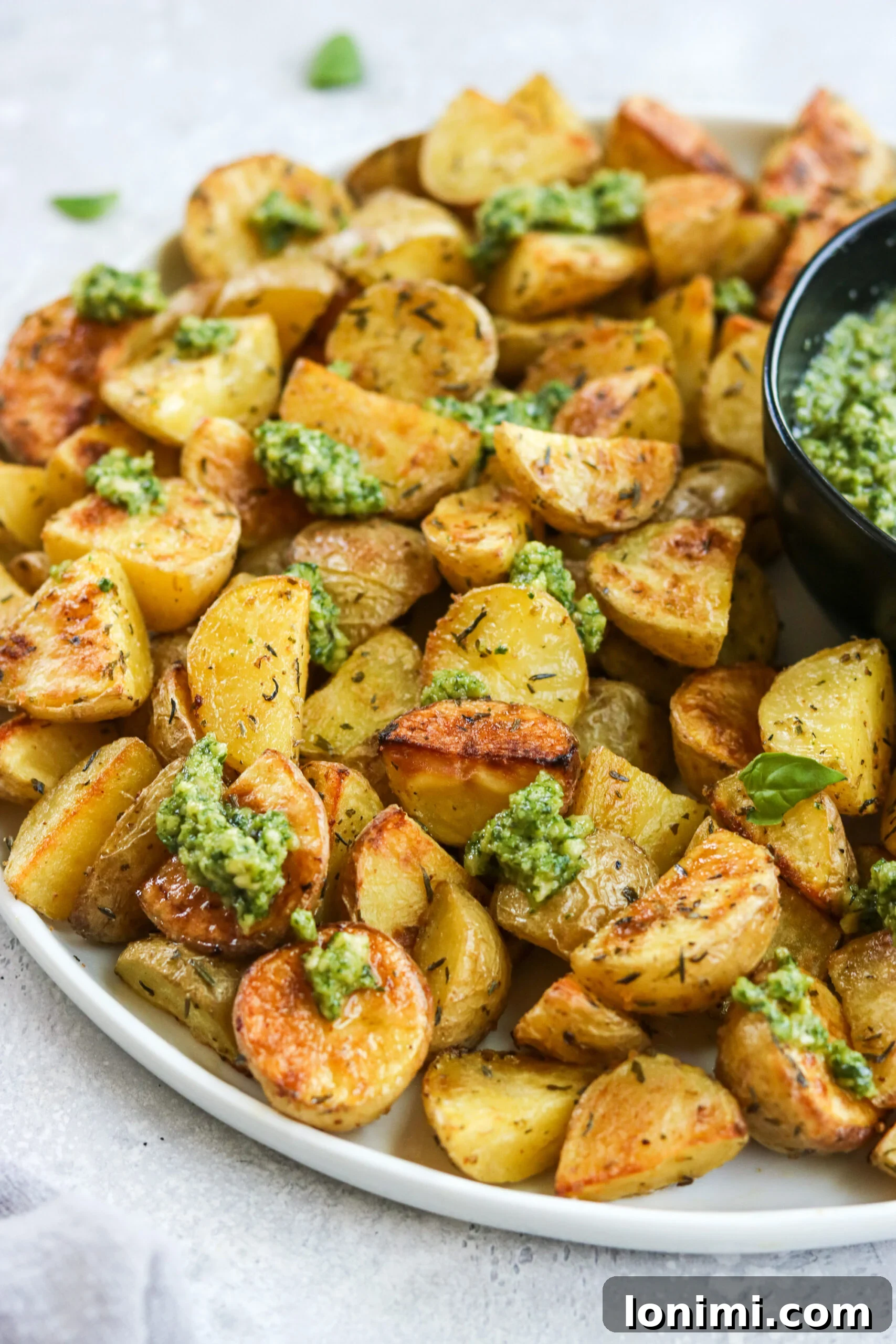 A plate of herb roasted potatoes topped generously with green cashew pesto