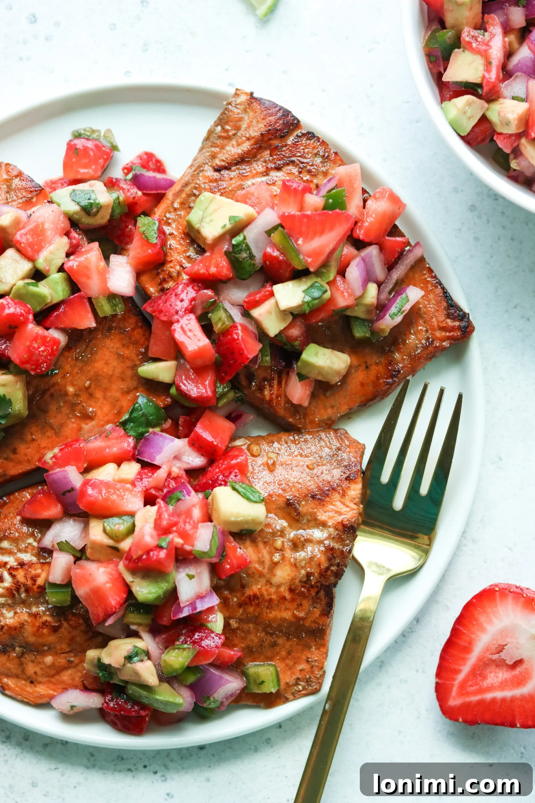 Balsamic Grilled Salmon with Strawberry Avocado Salsa on a plate, garnished with fresh herbs