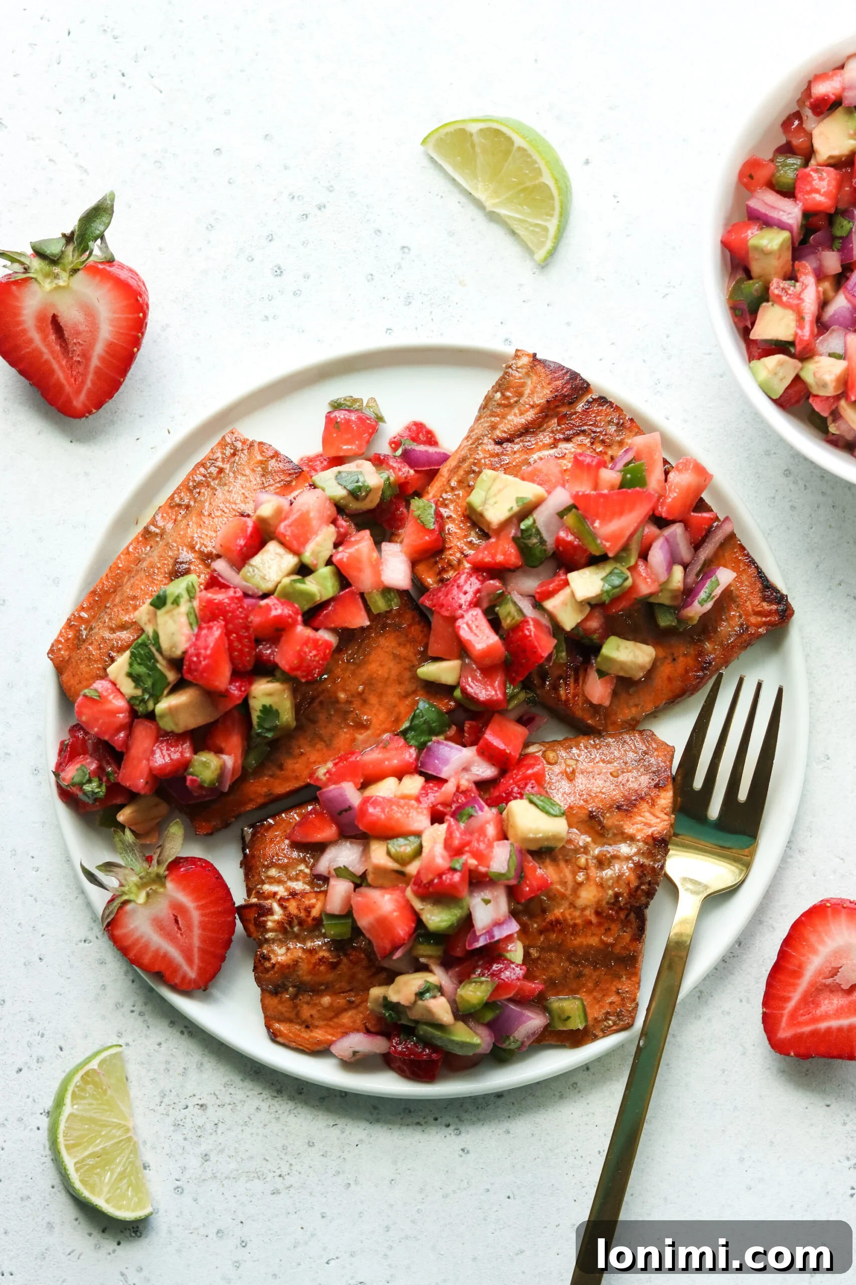 Close-up of grilled salmon fillet with strawberry avocado salsa on top, ready to serve