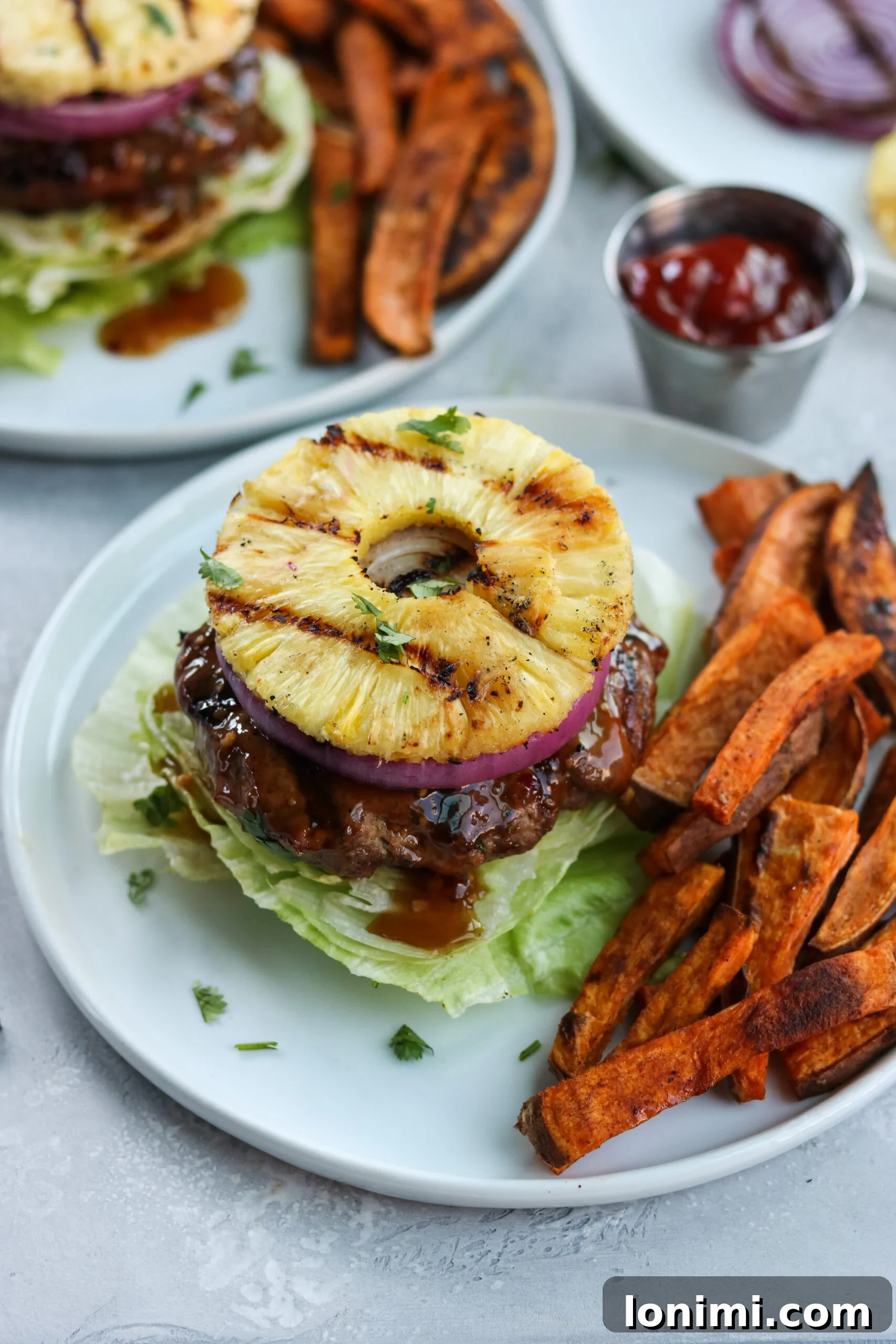 Tropical Teriyaki Whole30 Burgers with Grilled Pineapple 4 Grilled Whole30 Teriyaki Burgers with pineapple slices and red onion ready for assembly
