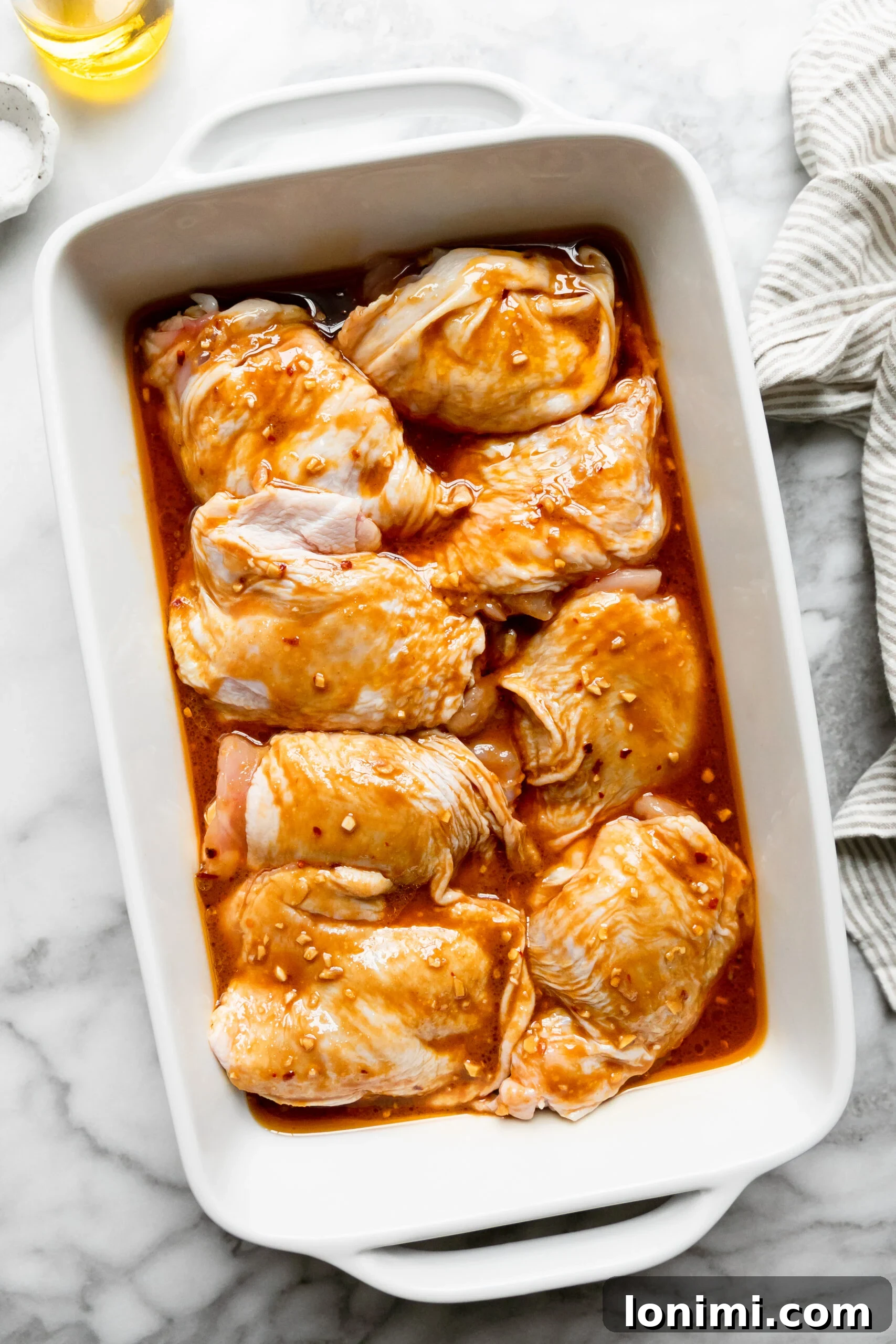 Keto Chicken Thighs Perfectly Marinated for Health and Flavor 6 a white casserole dish filled with raw chicken thighs drenched in marinade