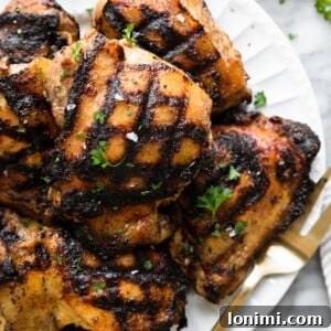 Keto Chicken Thighs Perfectly Marinated for Health and Flavor 8 grilled marinated chicken thighs on a white plate with a gold fork