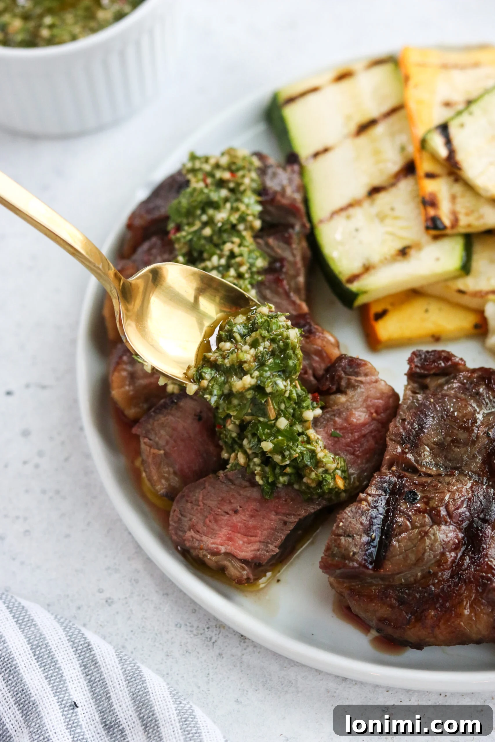 Beautifully cooked New York Strip steaks with a generous dollop of fresh chimichurri, garnished with fresh herbs and ready to be served.