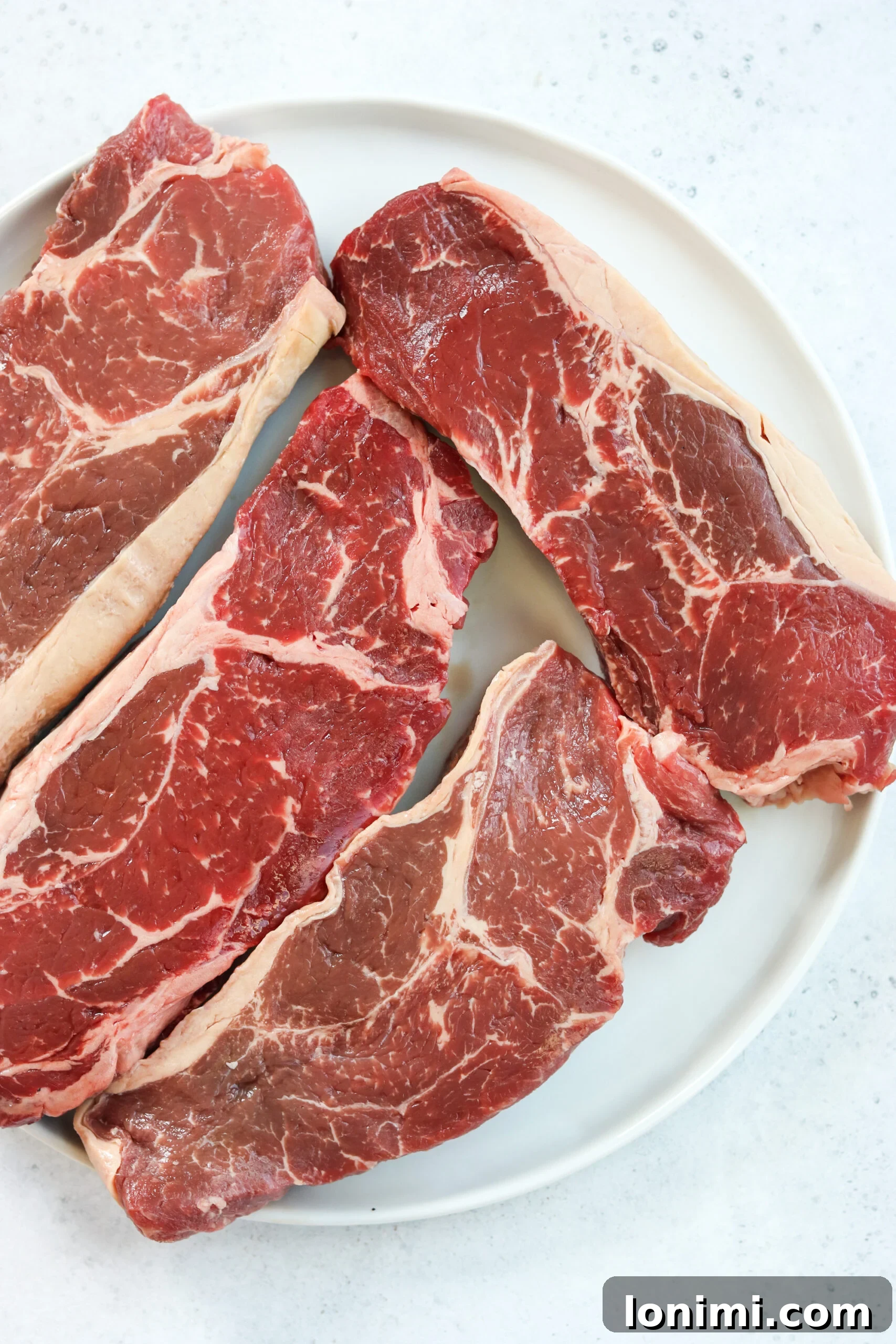 Close-up of raw Australian Grassfed Beef New York Strip steaks, showcasing their lean, high-quality appearance and readiness for grilling.
