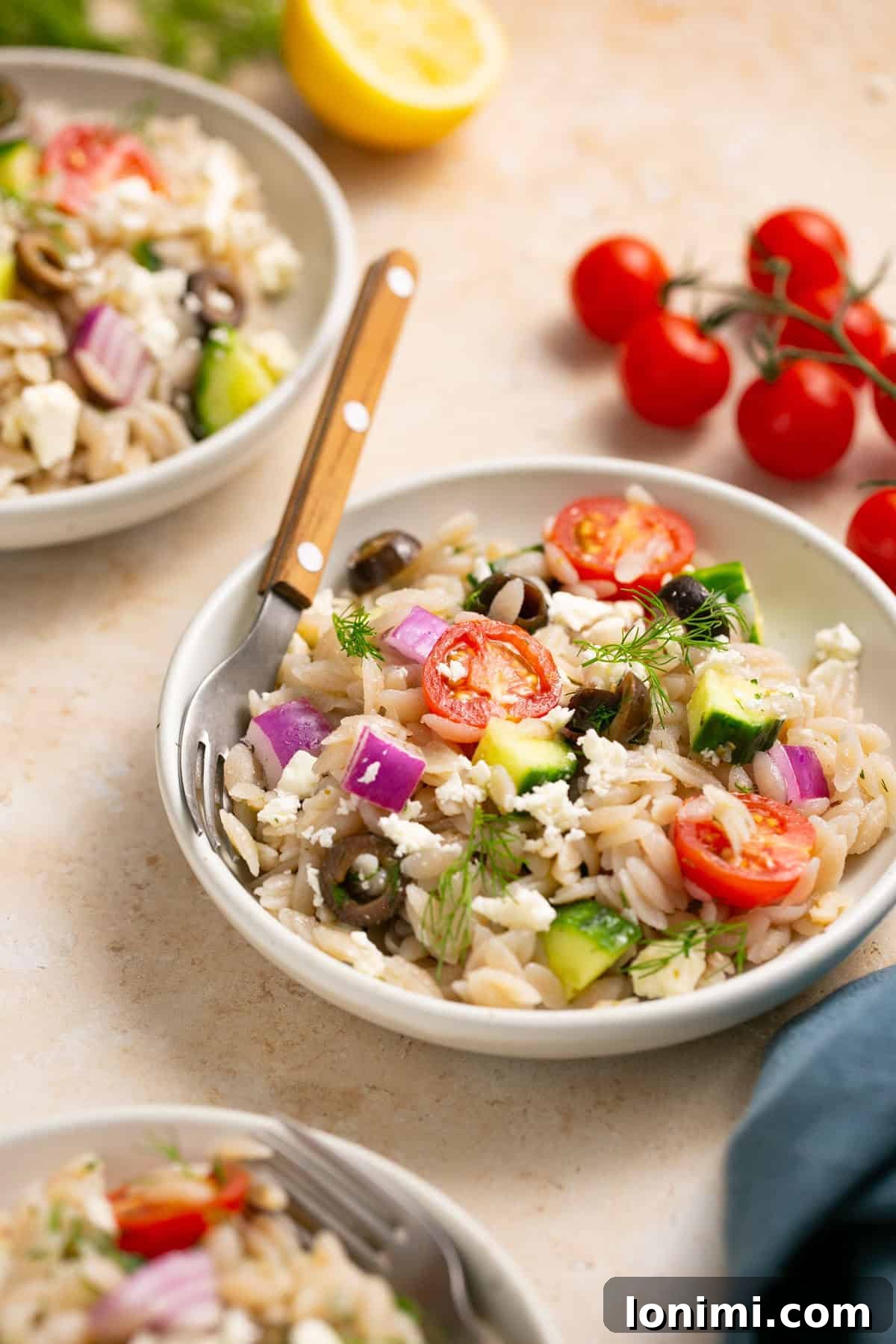 A single serving of gluten-free Mediterranean orzo salad in a small bowl with a fork, emphasizing its appetizing appearance.