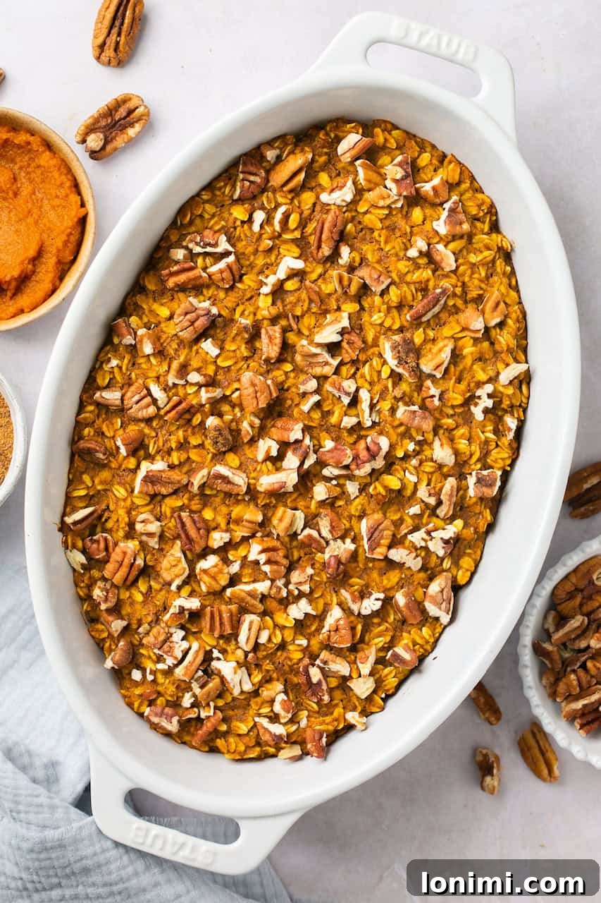Spiced Pumpkin Oatmeal Bake 5 A close-up shot of warm pumpkin baked oatmeal, neatly sliced and presented in a white ceramic Staub dish, ready to be served.