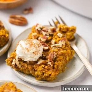 Pumpkin Baked Oatmeal on a plate with a dollop of whipped cream and a gold fork, symbolizing a comforting autumn breakfast.