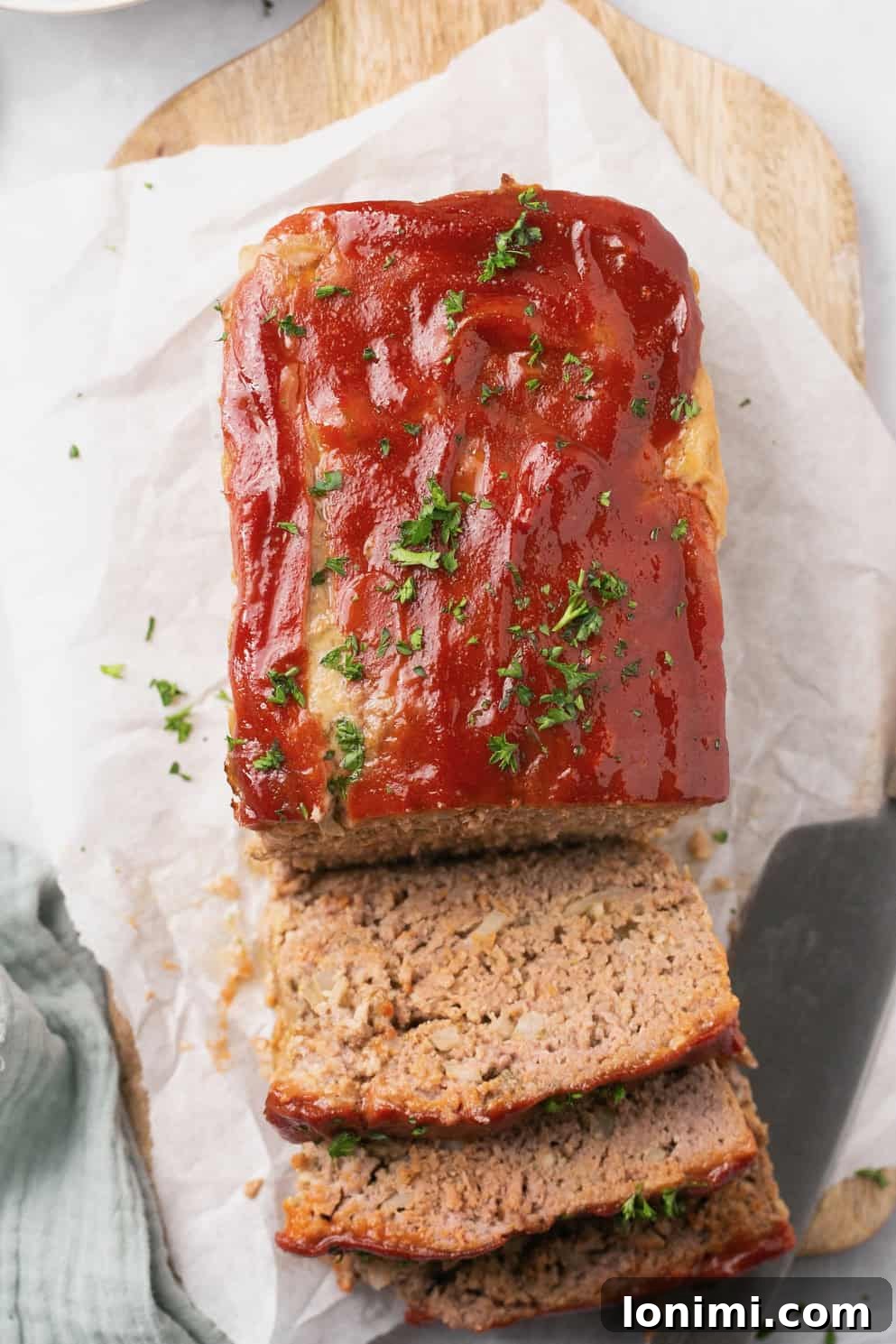 A perfectly sliced gluten-free meatloaf resting on a cutting board, topped with a glistening sweet and tangy glaze, ready to be served.