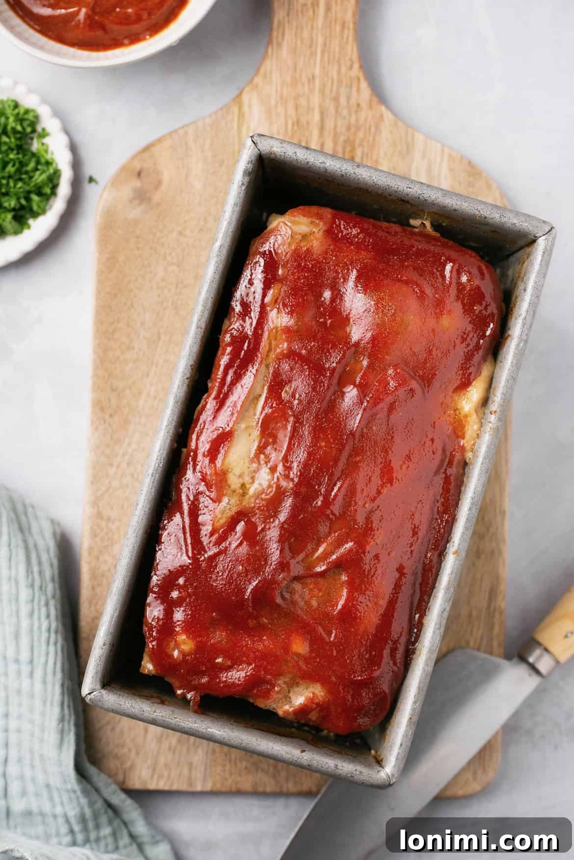 An overhead view of a perfectly baked and glazed meatloaf in a baking pan, fresh out of the oven.