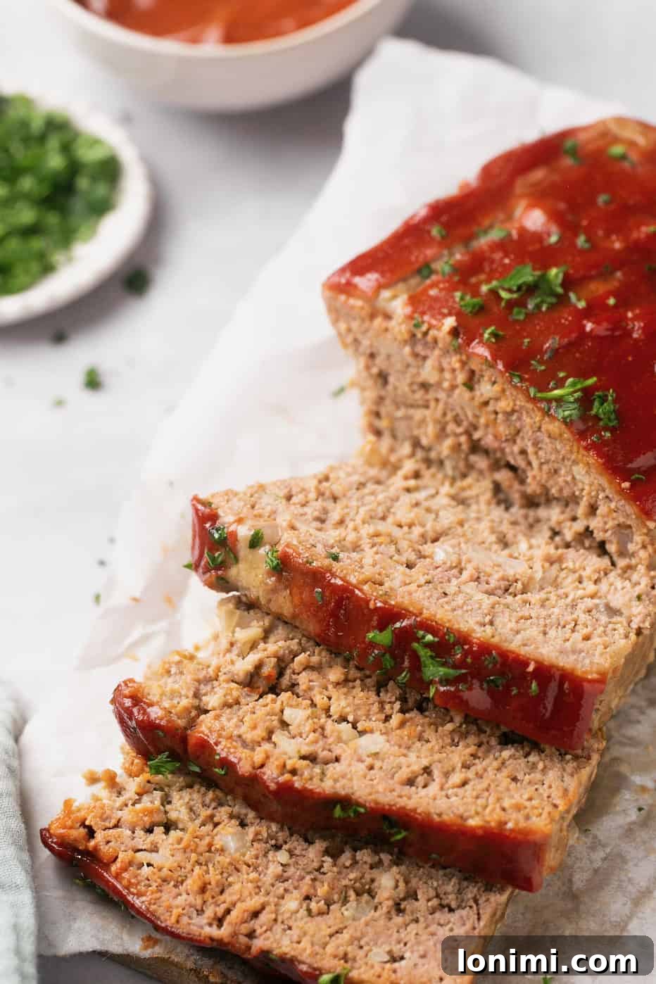 A beautifully garnished gluten-free meatloaf, topped with fresh parsley and expertly sliced for serving.