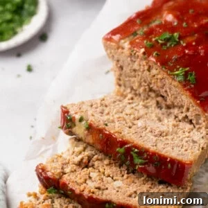 Gluten-free meatloaf topped with parsley, freshly sliced and ready for serving