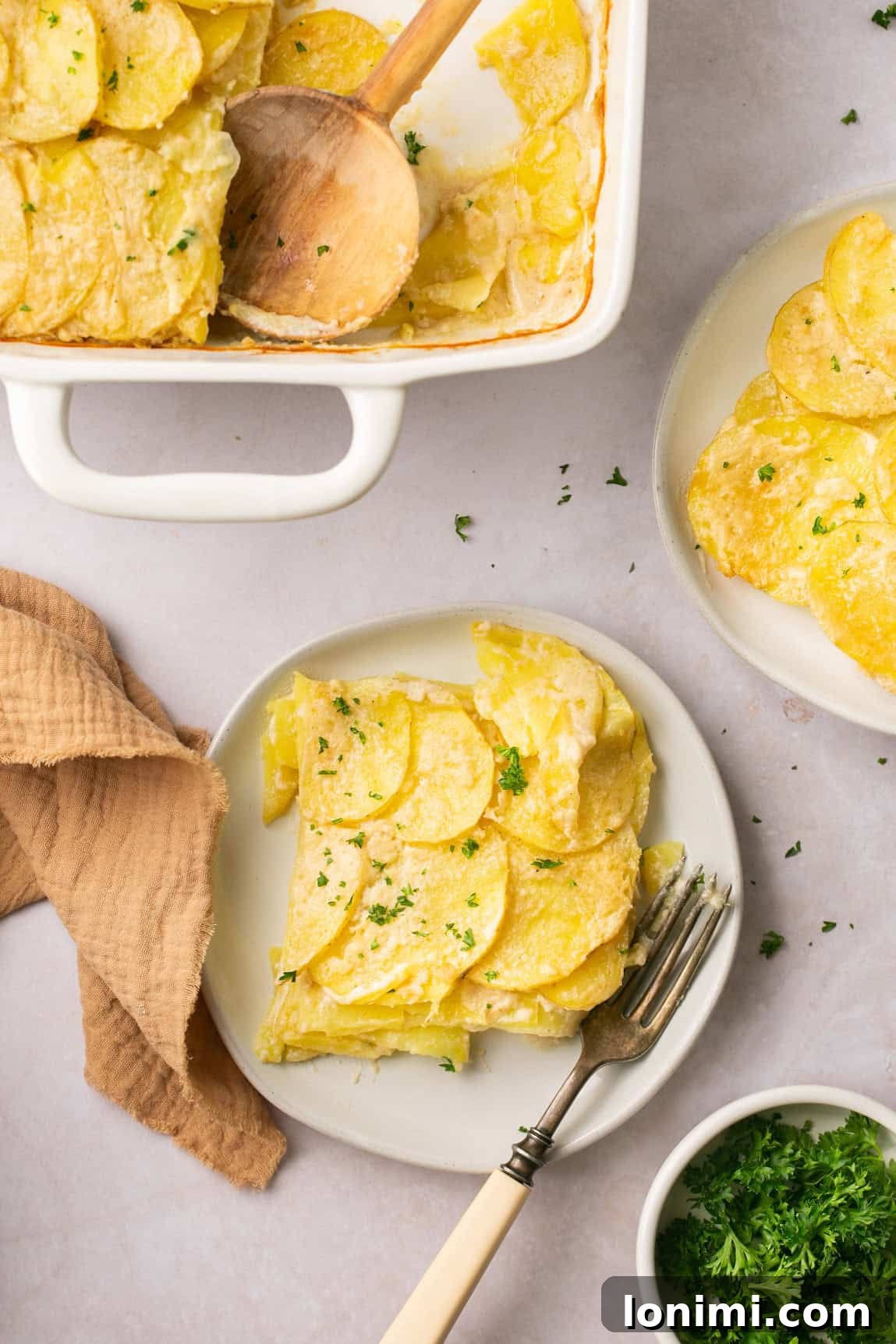 a serving of scalloped potatoes on a plate with a fork resting on the side