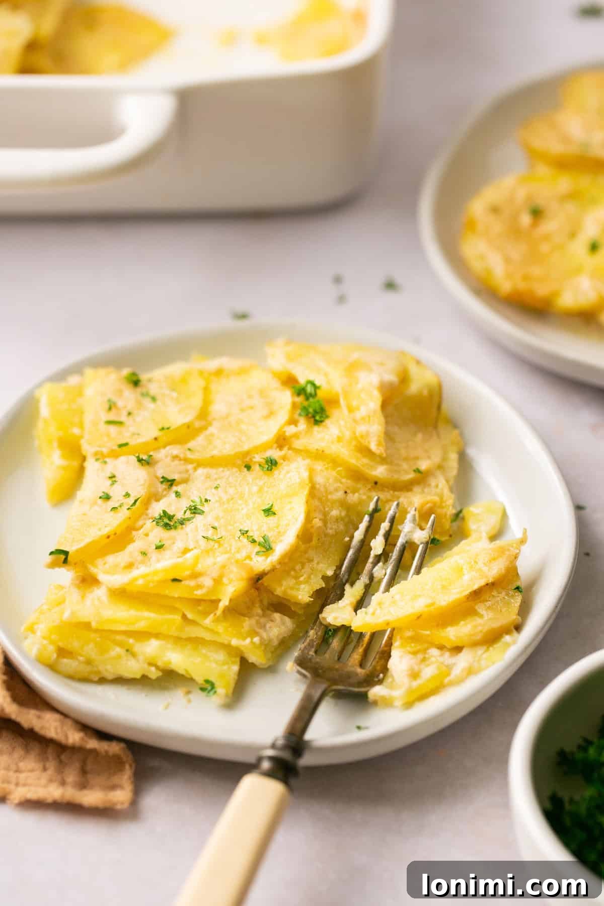 a closeup shot of a slice of potatoes on a plate with a fork resting on the side