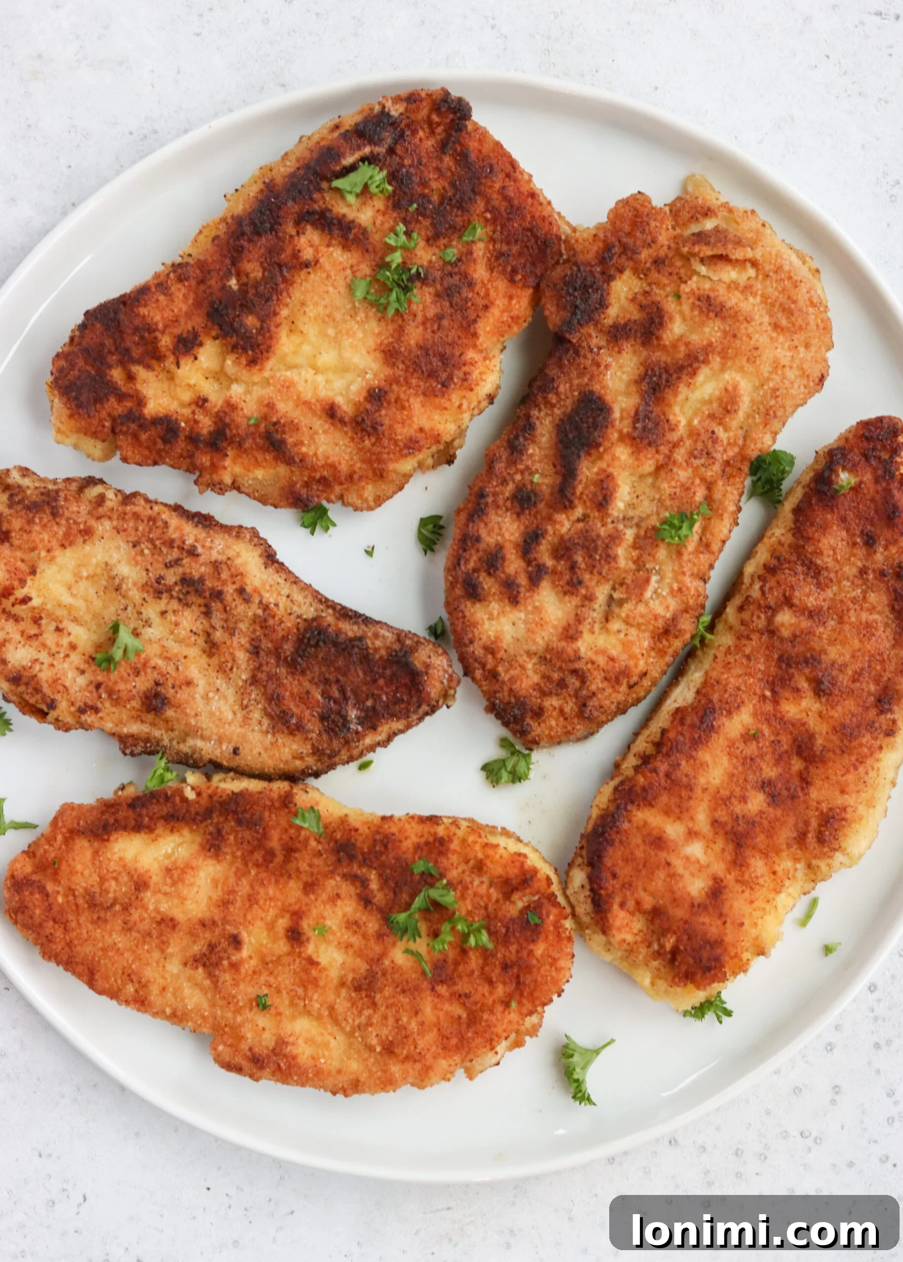 Golden brown Whole30 Fried Chicken Cutlets stacked on a plate, ready to be served.