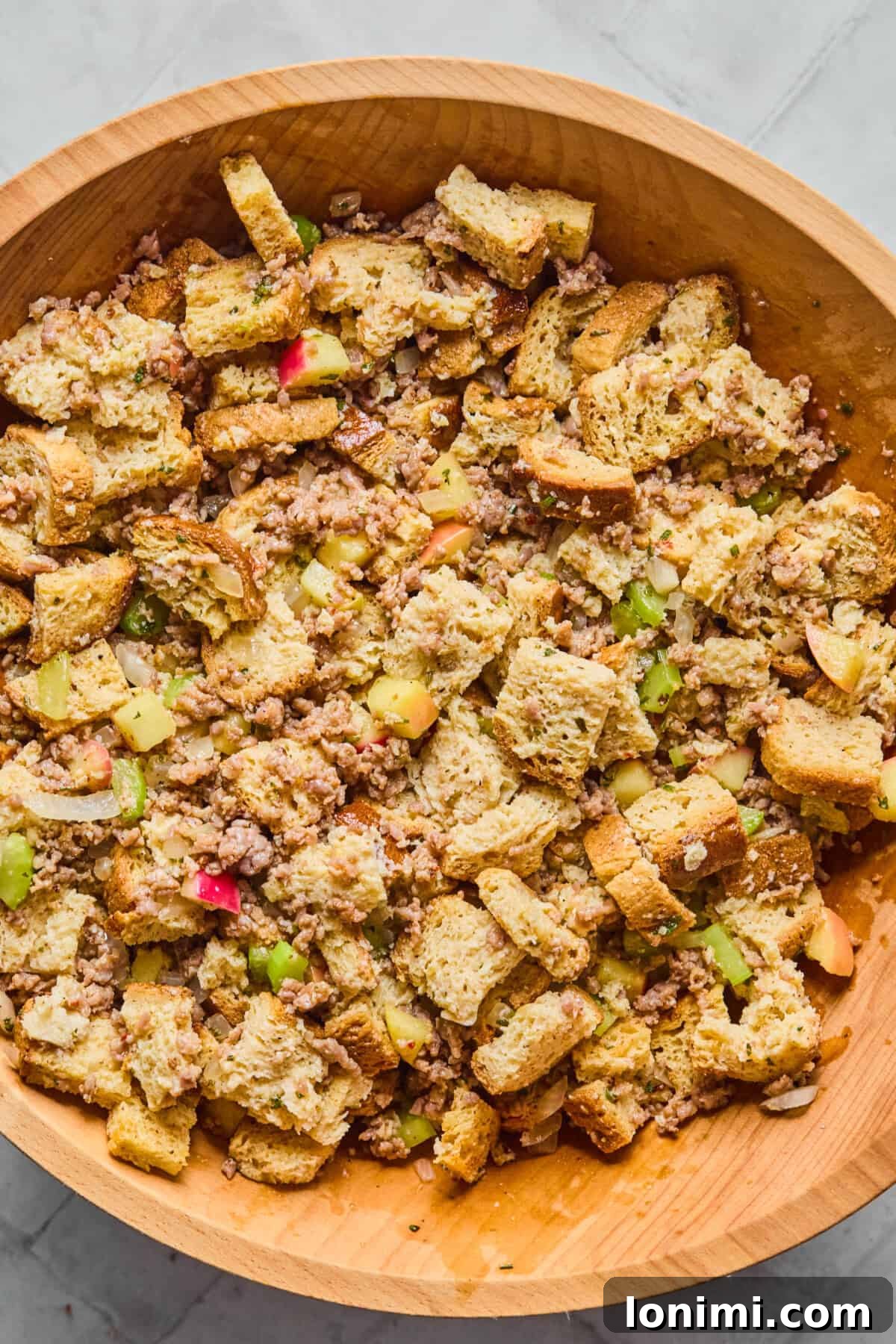 sausage, bread, celery, apples, herbs and broth in a bowl