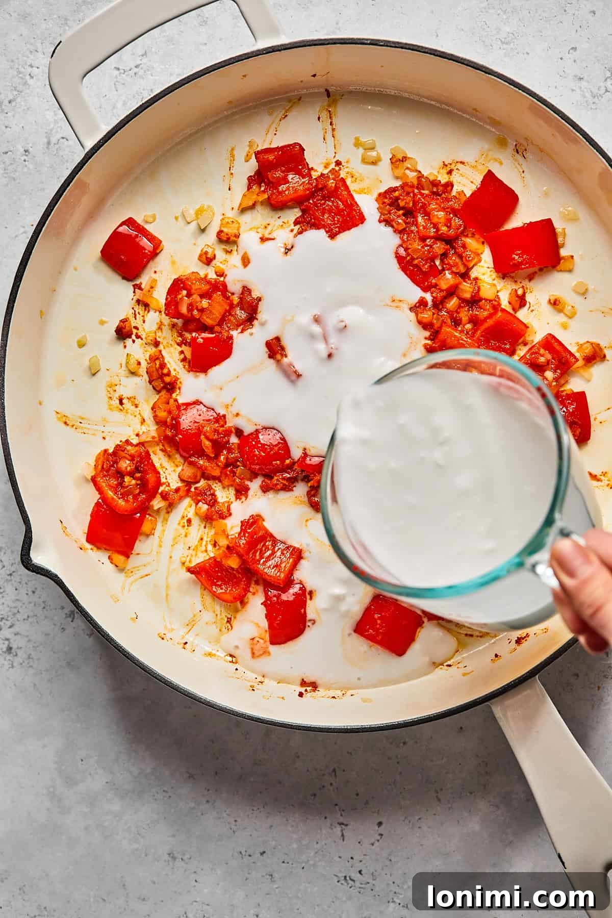 pouring coconut milk into a skillet 