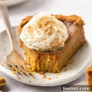 A slice of gluten-free pumpkin pie on a plate, topped with whipped cream.