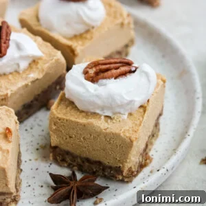 A square of Paleo Vegan Pumpkin Cheesecake, topped with whipped cream and a pecan.