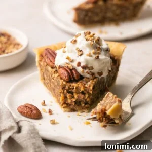 A slice of gluten-free pecan pie without corn syrup, topped with whipped cream, with a fork taking a bite.
