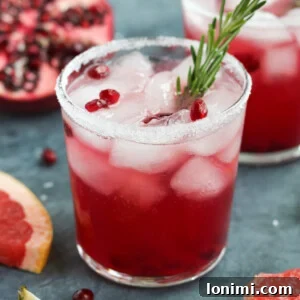 A Pomegranate Paloma cocktail with fresh lime and pomegranate seeds.