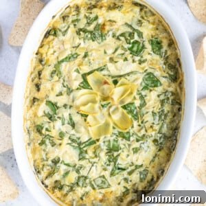 Creamy Paleo Spinach Artichoke Dip, made with cashews, served with vegetable sticks.