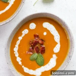 A bowl of rich butternut squash soup, garnished with crispy bacon and fresh sage.