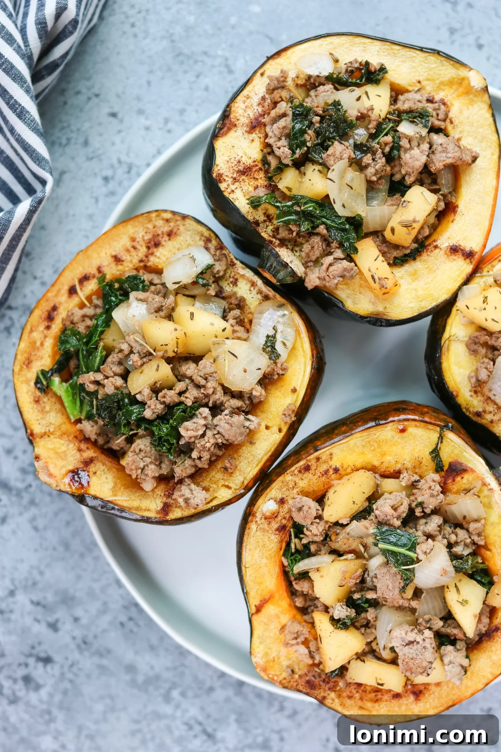 Two halves of golden roasted acorn squash filled with a rich, savory stuffing