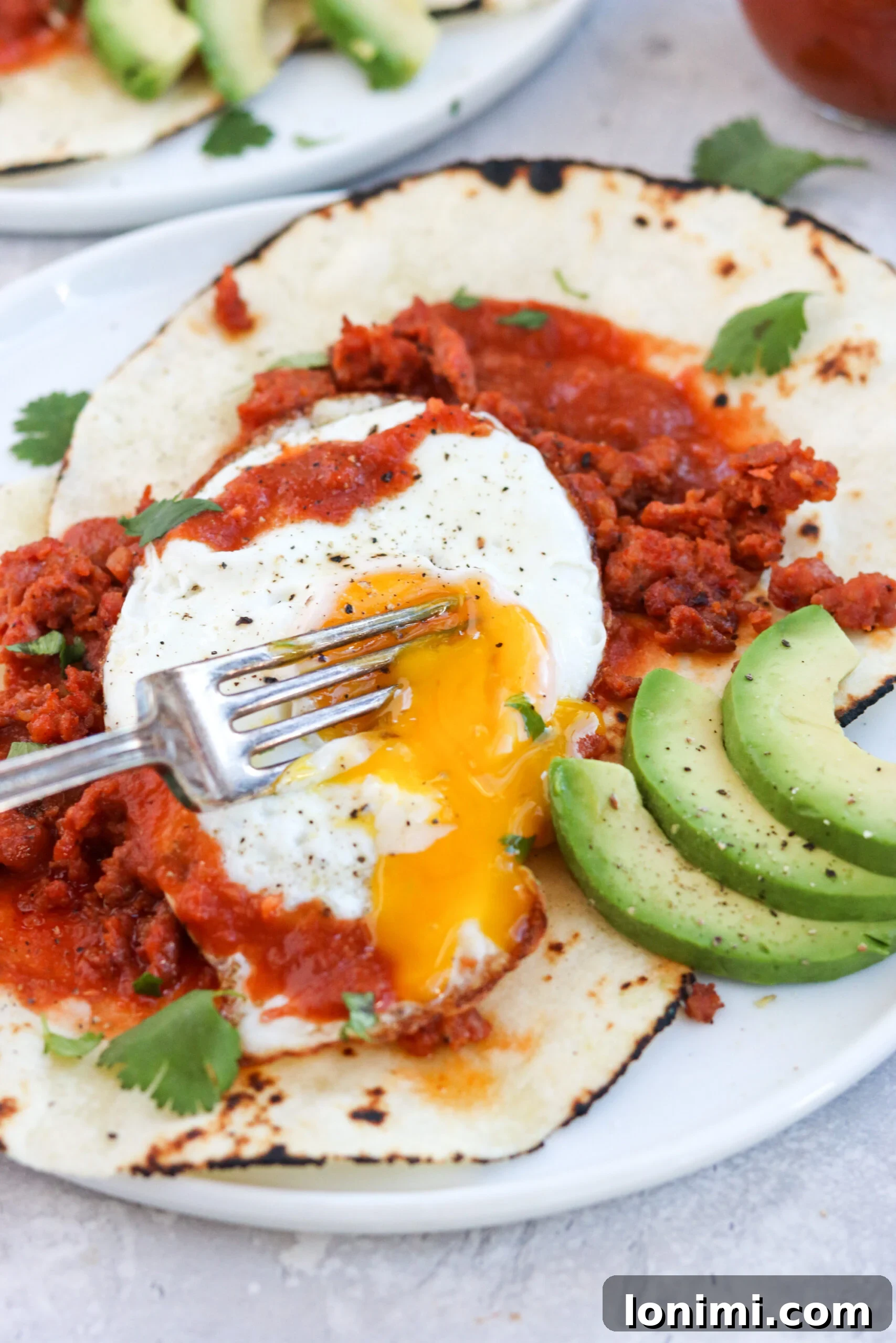 Close-up of a perfectly runny egg yolk on Paleo Huevos Rancheros, garnished with cilantro