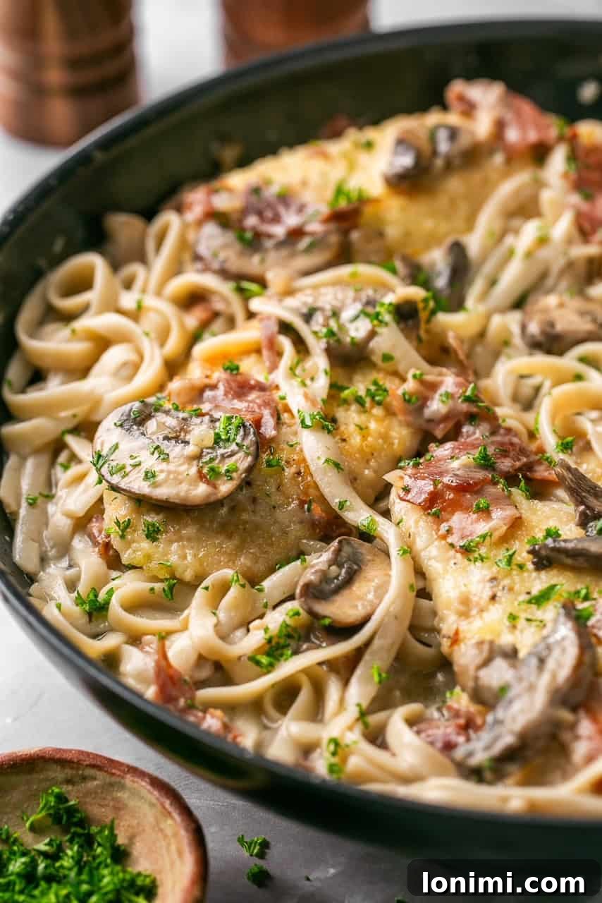 chicken marsala fettuccine in a skillet topped with parsley