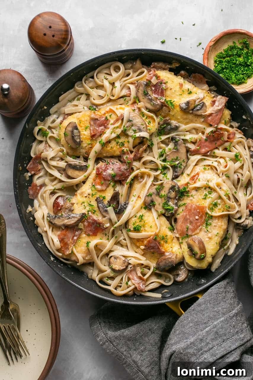 a skillet with fettucine and chicken marsala topped with parsley