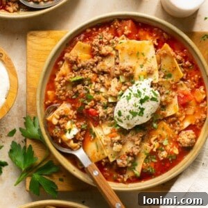 Gluten-free lasagna soup in three bowls with a dollop of ricotta and parsley on top.