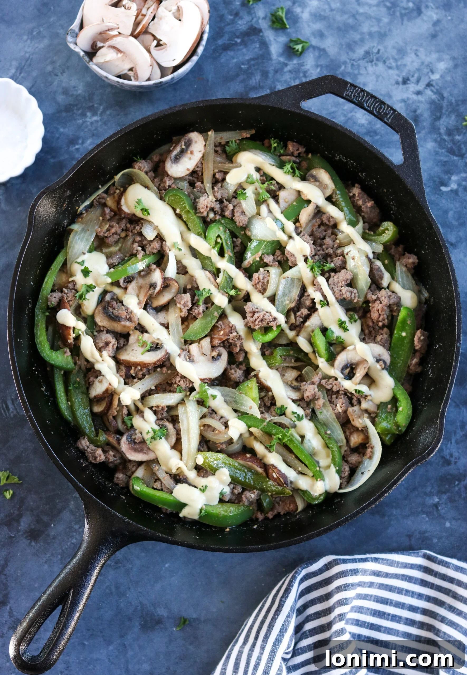 A vibrant Whole30 Philly Cheesesteak Skillet, showing ground beef, bell peppers, onions, and mushrooms cooked to perfection, topped with a creamy dairy-free cheese sauce.